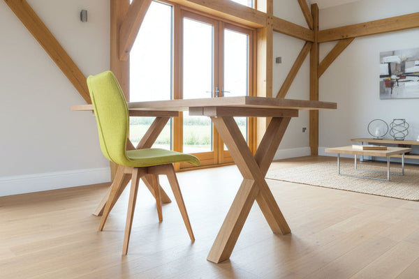 Side view of handmade petit cross leg table with quad pod chair in oak framed modern house