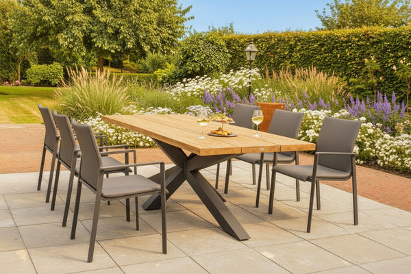 Oak garden table with steel base on patio with naturalistic planting in background