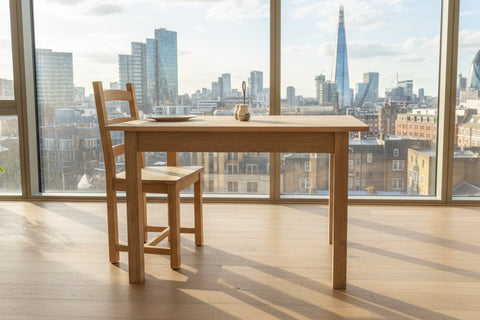 Small handmade oak table side view in London apartment with views over the city