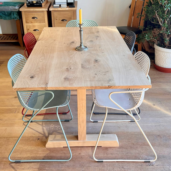 End and top view of handmade Sussex oak fine pillar dining table with colourful stacking chairs