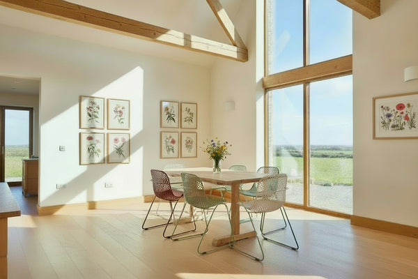 Dining area with a handmade Sussex solid oak fine table and colorful chairs near a large window