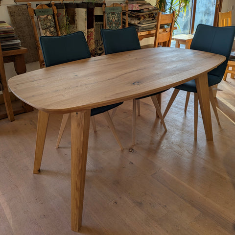 Solid ak Curved Dining Table with splayed legs and an oiled finish