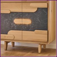 A mid-century modern wooden cabinet with a light natural wood frame, dark gray ceramic front panels, and light wood geometric handle details, shown on a wooden floor.