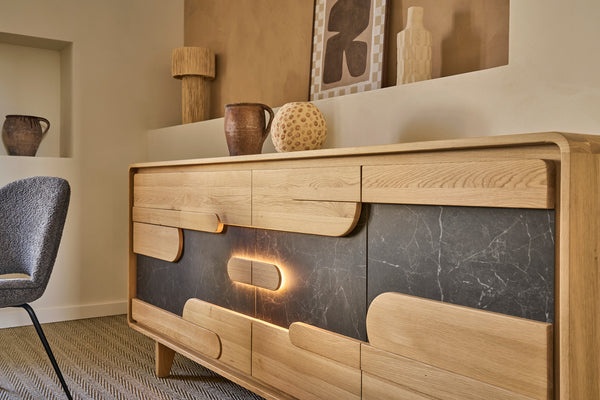 A modern wooden sideboard or credenza with a light oak finish and dark gray ceramic inlay panels, shown in a styled interior room setting.