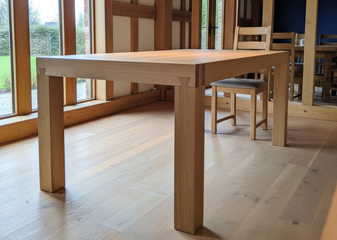 Tuscany Terra oak dining table on a wooden floor with chairs in the background