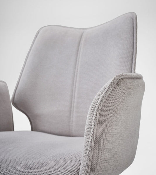 Close-up of a light gray upholstered chair showing the backrest, armrest, and textured fabric against a plain light background.