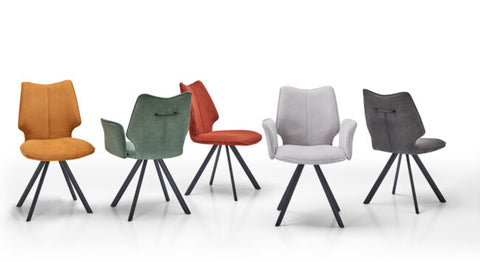 Five modern dining chairs with sculptural wingback backs and black metal tripod legs, shown in orange, sage green, rust red, light gray, and charcoal gray upholstery on a white studio background.