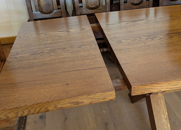 Close-up of extension leaf for cross leg oak dining table with a chair in the background.