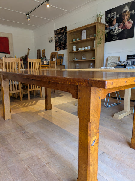 A rustic rectangular wooden dining table with thick legs and a medium oak finish, 