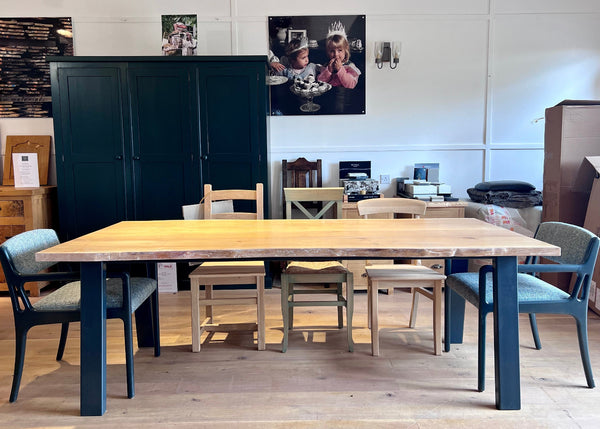 Waney (live) edge oak table with a powder coated steel base in a showroom setting
