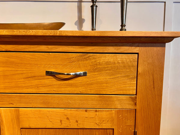Close-up of drawer front of the Staplecross oak sideboard on a white background