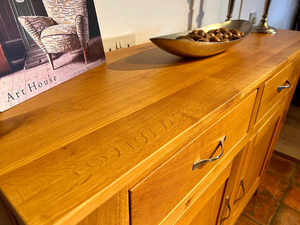 Top view of the Staplecross oak sideboard with a bowl of nuts and a picture on top, on a tiled floor.