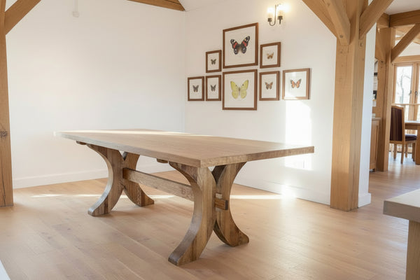 Handmade Moselle oak dining table with curved legs in a an oak framed house with British butterfly artwork on the walls