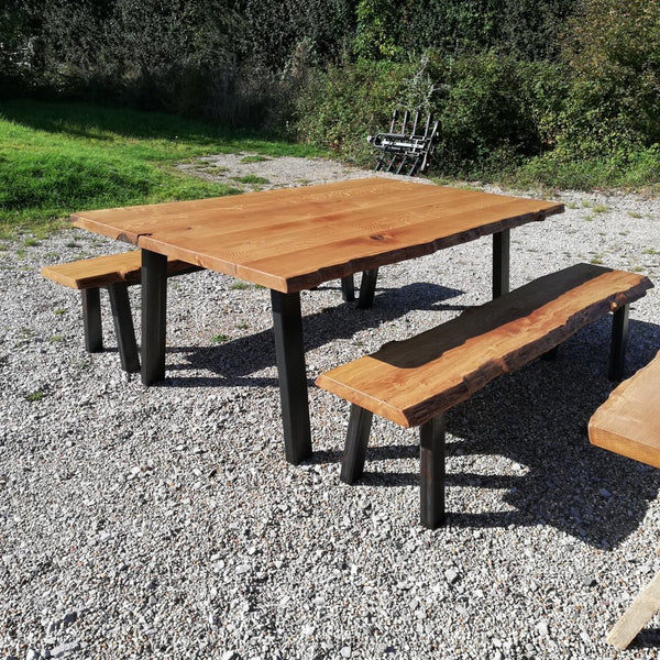 Live edge table on steel base with matching benches outside of our showroom