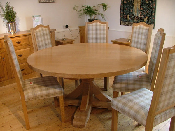 Swailes round oak dining table with braced pedestal and upholstered chairs