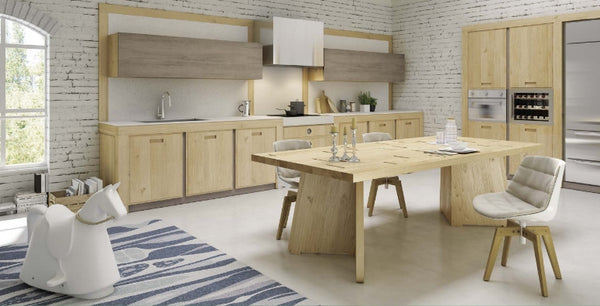 Modern oak wedge dining table with a thick tabletop and a distinctive wedge-shaped base, placed in a bright kitchen setting with wooden cabinets and a white countertop.