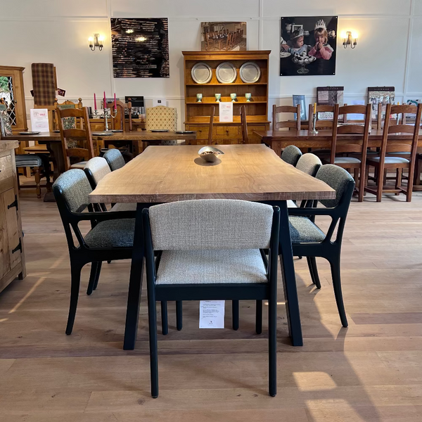 Sussex handmade live edge oak table on a bespoke handmade steel base  with a set of chairs end view in our showroom